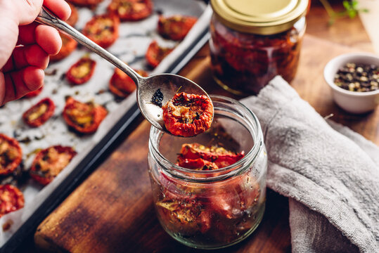 Preserving of Freshly Oven Baked Tomatoes with Thyme and Olive Oil in a Glass Jar