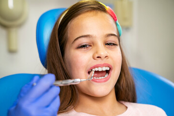 Cute little girl having routine dental checkup closeup 