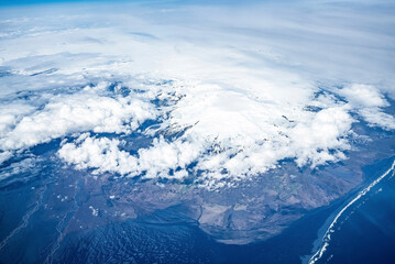 Fototapeta na wymiar Aerial view of beautiful snow covered white mountains. Scenic view of ocean and landscape covered with cloudscape from drone. Concept of picturesque nature in Alpine region.