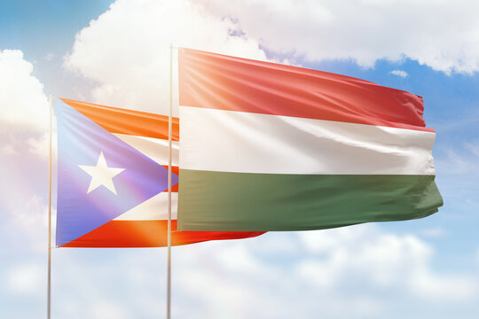 Sunny blue sky and flags of hungary and puerto rico