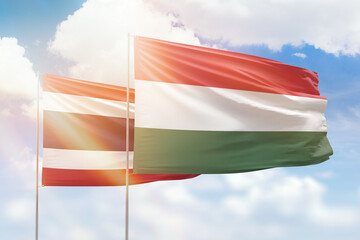 Sunny blue sky and flags of hungary and thailand