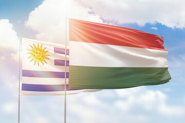 Sunny blue sky and flags of hungary and uruguay