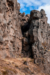 Dried grass against rock formations. Low angle view of majestic cliff against cloudy sky. Concept of beautiful rural wilderness natural environment in northern Alpine region.