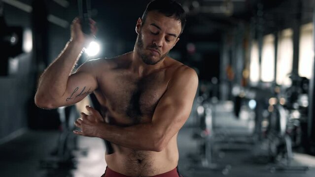 A muscular sportsman is doing exercise in the gym. Self confident man is holding nunchuck and practicing kung fu. Maximum focus and strength. Concept of martial arts health and sports.