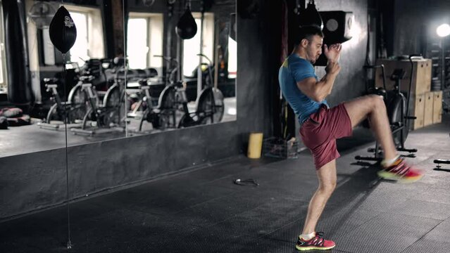 A muscular sportsman is doing exercises. Athlete is warming up before boxing workout in the dark gym. Sport training. Maximum focus and strength. Concept of lifestyle fitness health and sports.