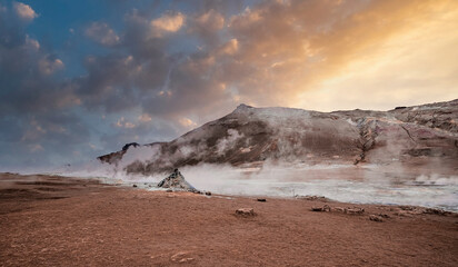 Steam emitting from geothermal area of Hverir against sky. View of Sulphur dioxide erupting from volcanic crater at Namafjall. Geyser in famous tourist attraction during sunset.