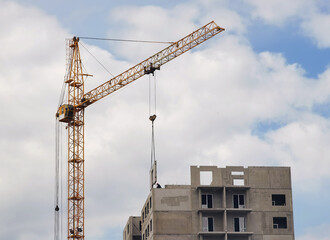 Crane and unfinished house. Building construction. A Crane is pulling a detail of a house.