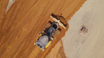 Fotobehang Vrachtwagen Top down drone shot of a bulldozer working on the construction site. High quality photo  © PoppyPix