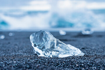 Close-up of beautiful iceberg on black sand of Diamond beach. Focus is on transparent frozen...