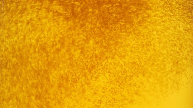 Pouring beer into glass. Closeup slow motion shot. Bubbles rising up