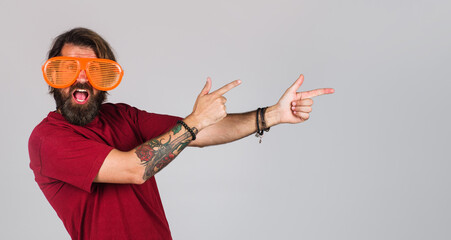 Bearded man pointing fingers to empty space. Funny guy in big glasses. Sale. Discount. Advertising.