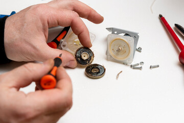 a service engineer is disassembling an old pump from a thermopot. maintenance of a broken thermopot.