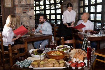 Closeup of served table with traditional dishes and wine in cozy rustic restaurant..