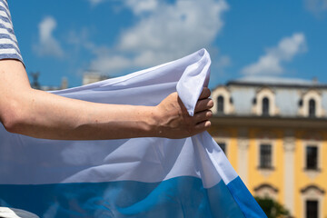 A young man's hand holds a white-blue-white flag used by Russian protesters against the Russian...