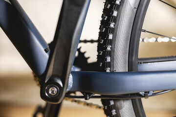 Fototapeta premium Part of a blue bicycle frame with off-road tires on the rear wheel, with one star on the cranks and a chain, close-up