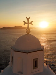 Cross of the Greek white church during sunset.
