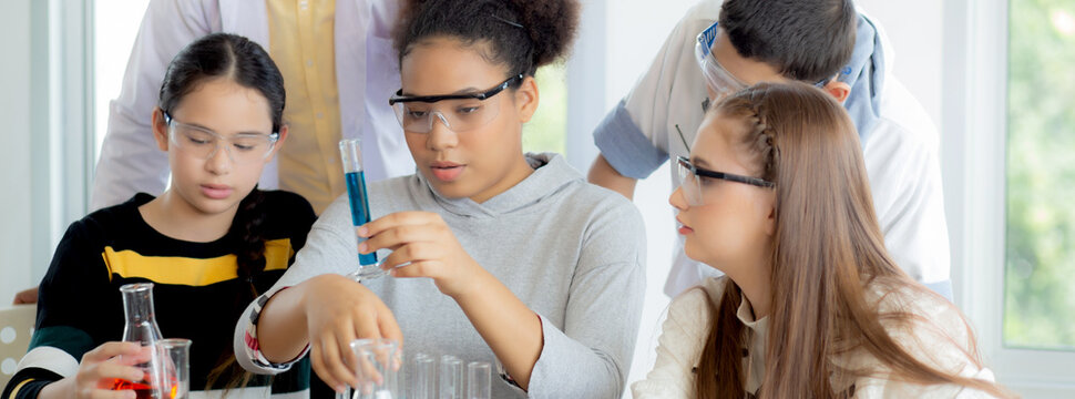 Young teacher teaching group student about science and test chemical for liquid in the lab of school, children studying and learning experiment science in the laboratory, education concept.