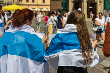 Russian activists wearing a white-blue-white flag on their backs on a sunny day participate in an...