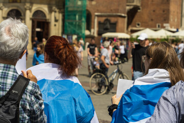 Fototapeta premium Russian activists wearing a white-blue-white flag on their backs on a sunny day participate in an anti-war protest in a European country against the Russian invasion of Ukraine
