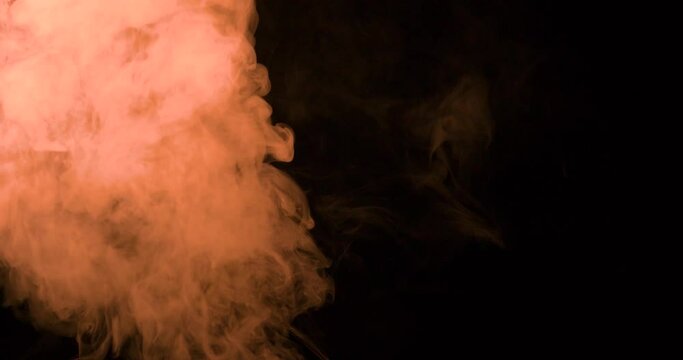 Textura de humo con densidad de color naranjo sobre fondo negro 