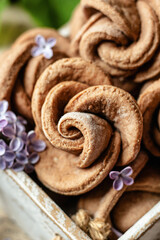 Homemade cottage cheese cookies shape rose in a rustic wooden box with lilac flowers close up