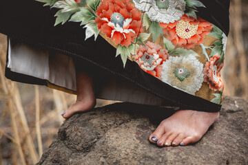 Closeup of beautiful old traditional black kimono with flowers and sexy japanese woman feet over a...