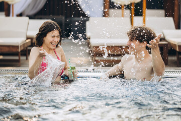 The guy flirts with a girl in the jacuzzi. Couple relaxing in the pool and enjoying the summer.