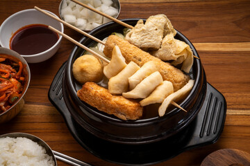 Fishcake with fish and vegetable soup in hot iron pot, Fishcake in bamboo skewers in iron pot on wooden table.