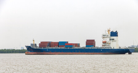 The Container Ship loaded of containers sail beside a seashore