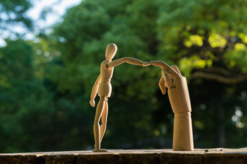 夏の公園にある木製マネキン人形と人形の片手との交流