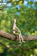 夏の公園で擬人化で撮影した木の枝に座る面白いマネキン人形の姿