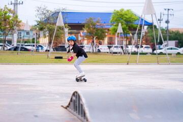 Child or kid girl playing surfskate or skateboard in skating rink or sports park at parking to wearing safety helmet elbow pads wrist and knee support