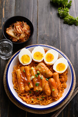 Korean spicy instant noodle with Tteokbokki, sausage and egg on wooden background