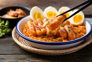 Korean spicy instant noodle with Tteokbokki, sausage and egg on wooden background