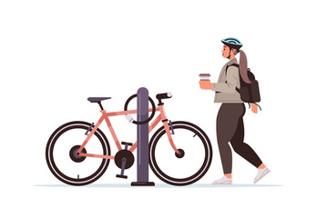 female cyclist taking break during bike ride woman in helmet with takeaway coffee cup standing near bicycle