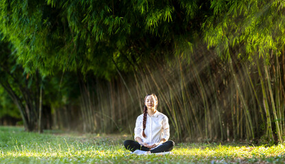 Woman relaxingly practicing meditation in the bamboo forest to attain happiness from inner peace...