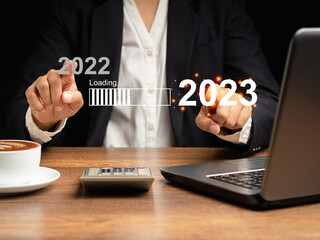 Hands touching on text 2022 to 2023 on the virtual download bar with loading progress bar for New Year's Eve and changing the year
