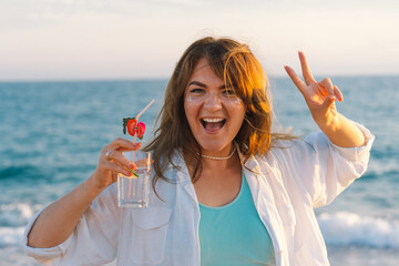 Portrait of a happy young girl with a cocktail in hand on a background of beautiful sea. Girl...