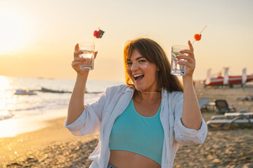 Portrait of a happy young girl with a cocktail in hand on a background of beautiful sea. Girl having fun on summer vacation. Freedom and happiness © Анастасія Стягайло