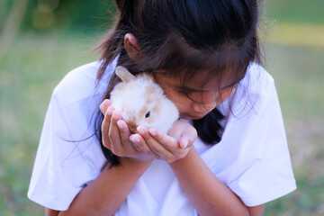 Asian girl holding adorable bunny fluffy in hand with tenderness and love. People take care and...