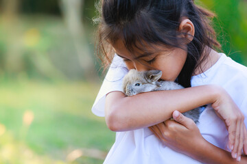 Asian girl holding adorable bunny fluffy in hand with tenderness and love. People take care and...