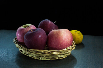 Still life of apple and orange fruit on against dark background.