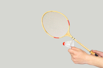 man's hand holding a badminton racket on grey background.