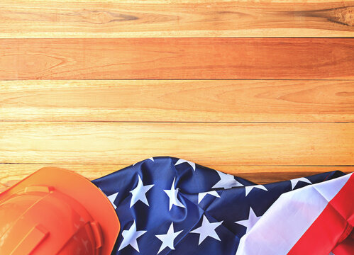 Top view with orange safety helmet and usa flag on wood table background.