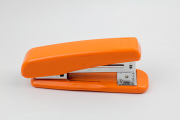 orange big stapler on white background in studio