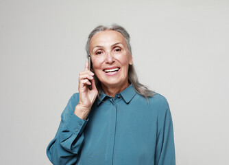 Elderly smiling happy woman 70s wear blue shirt talk speak on mobile cell phone