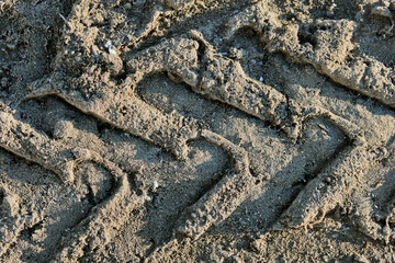Tread track of wheeled tractor on frozen dirt road, texture for background.
