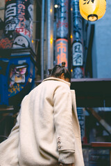 A woman with her back turned in the streets of the city in the Japanese quarter. Vertical photo.