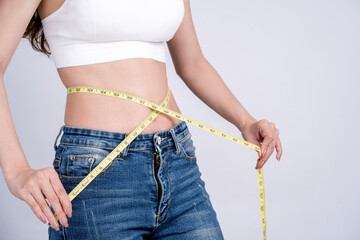 Woman in jeans with tape measure show thin body.Diet and weight control. Weight loss and slimming concept. - obrazy, fototapety, plakaty
