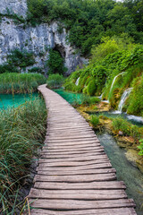 Plitvice, Croatia - Wooden walkway in Plitvice Lakes National Park on a bright summer day with crystal clear turquoise water, green summer foliage and small waterfalls
